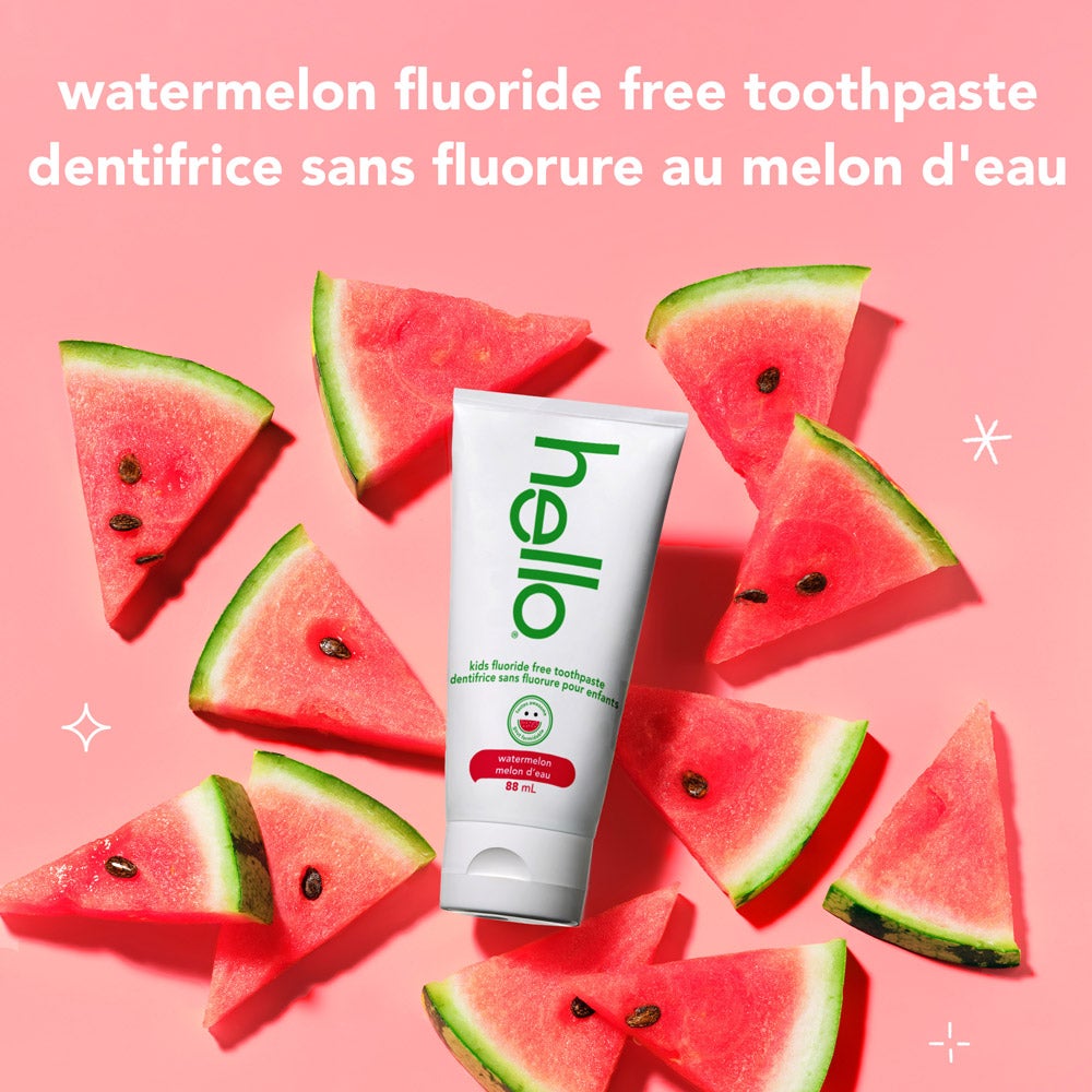 A hand holds a tube of Hello watermelon fluoride-free toothpaste against a pink background. White text beside the product says, "tastes awesome, works brilliantly. removes plaque*. polishes + brightens." At the bottom, there is a small note: "*with daily brushing."
