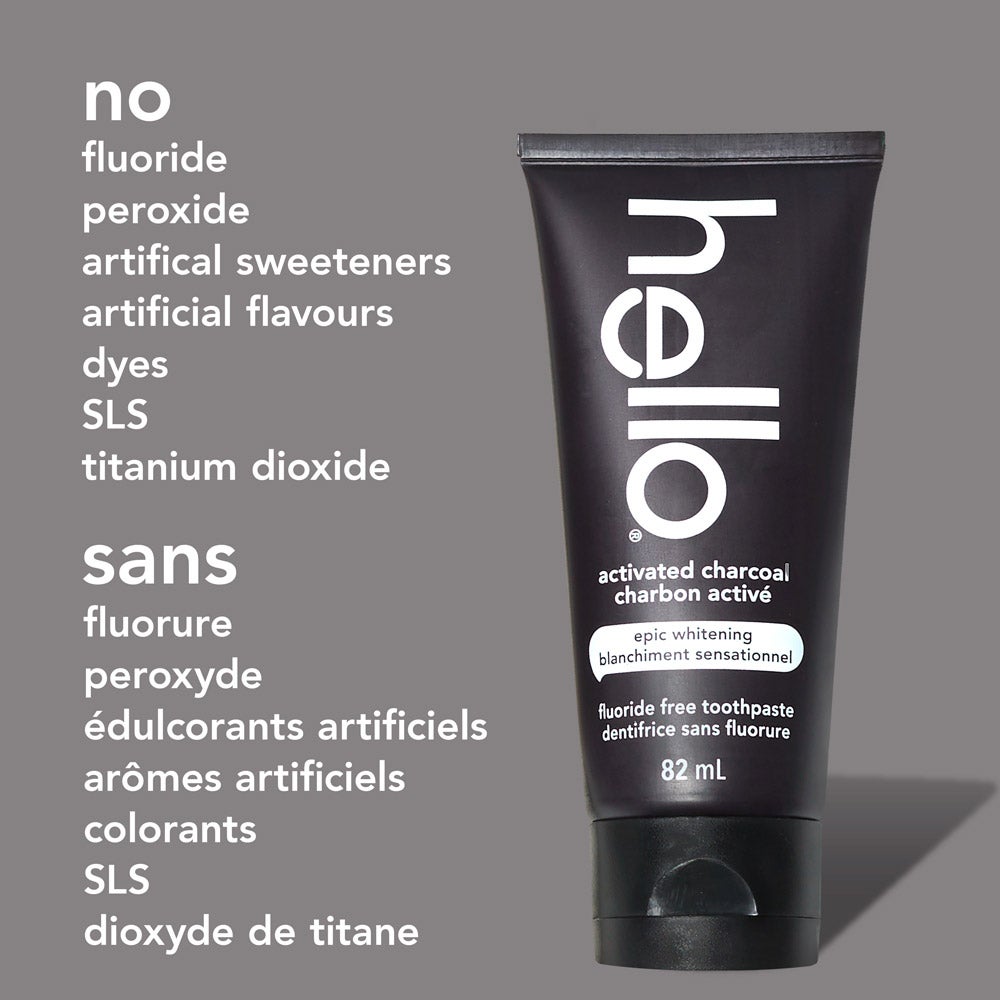 A tube of hello epic whitening charcoal fluoride free toothpaste stands upright against a light gray background. To the left of the tube, text lists: "no fluoride, peroxide, artificial sweeteners, artificial flavours, dyes, SLS, titanium dioxide" in English and the same in French below.
